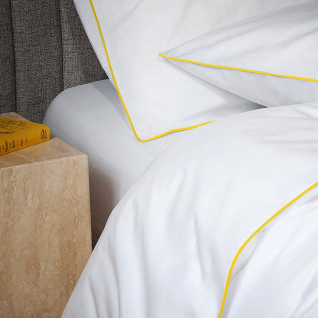 Bed sheets duvet and cushion in bed yellow piping